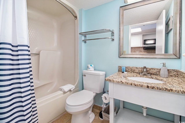bathroom with a textured ceiling, toilet, vanity, shower / tub combo, and tile patterned flooring