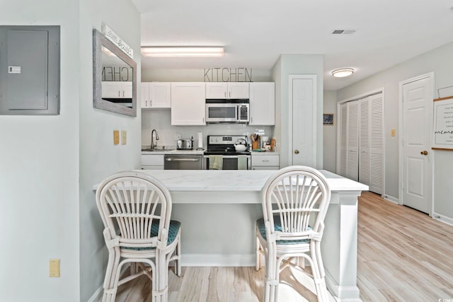 207 Double Eagle Dr Unit F-3, Myrtle Beach, SC 29575 - kitchen with stainless steel appliances, electric panel, a breakfast bar, and light wood-style floors