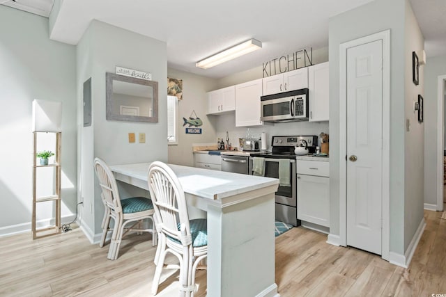 207 Double Eagle Dr Unit F-3, Myrtle Beach, SC 29575 - kitchen with stainless steel appliances, light wood finished floors, a kitchen breakfast bar, white cabinetry, and a peninsula