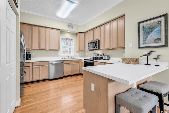 kitchen featuring stainless steel appliances, a peninsula, a kitchen bar, a textured ceiling, and light wood-style floors