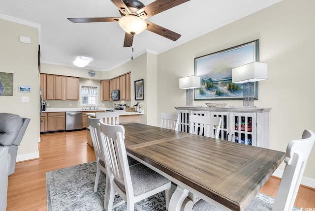 dining area with light wood-style floors, crown molding, ceiling fan, and baseboards
