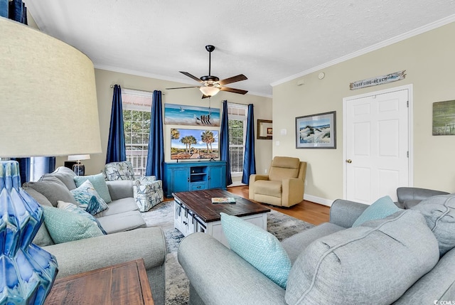 living room with ceiling fan, crown molding, wood finished floors, a textured ceiling, and baseboards