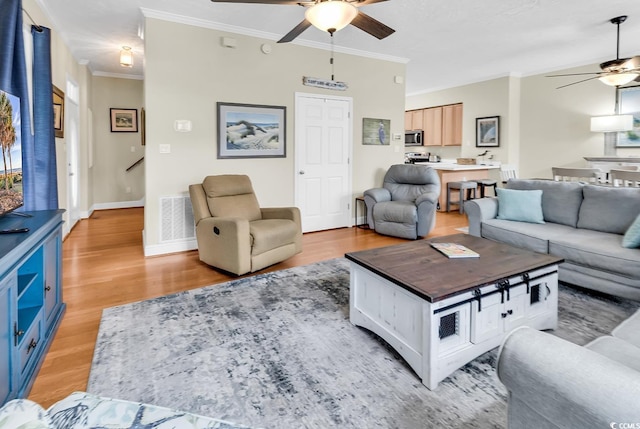 living room featuring a ceiling fan, crown molding, light wood-style flooring, and baseboards