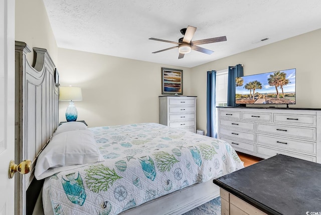 bedroom featuring wood finished floors, ceiling fan, and a textured ceiling