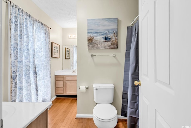 full bathroom featuring wood finished floors, vanity, baseboards, and toilet