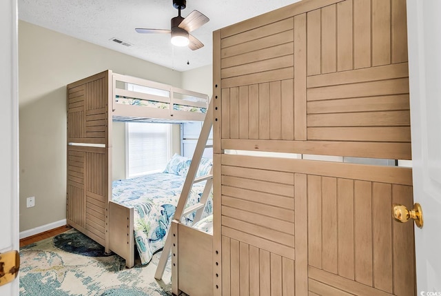 bedroom with baseboards, wood finished floors, a textured ceiling, and a ceiling fan