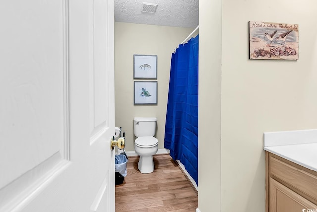 bathroom with wood finished floors, toilet, vanity, a textured ceiling, and a shower with shower curtain