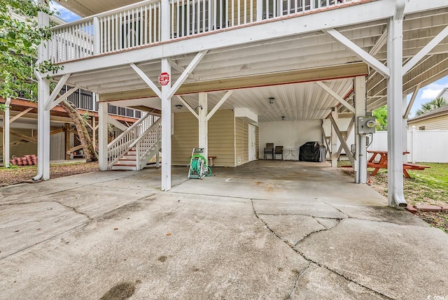 view of vehicle parking with driveway, a carport, stairs, and fence