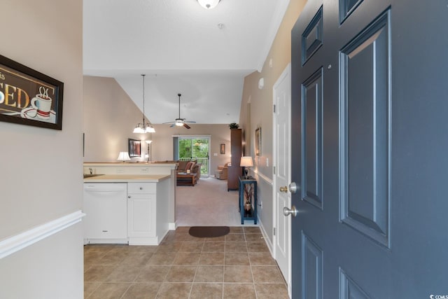 foyer entrance featuring vaulted ceiling, light tile patterned floors, light colored carpet, and ceiling fan