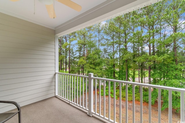 balcony featuring a ceiling fan and view of scattered trees