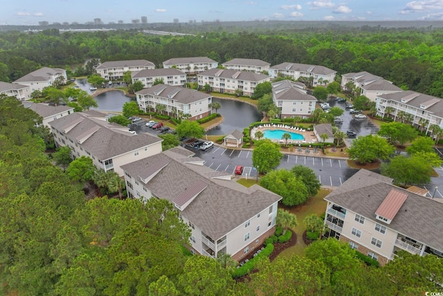 aerial perspective of suburban area featuring a pool area, a large body of water, and a forest