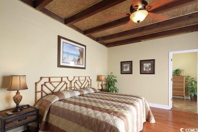 bedroom with beamed ceiling, wood finished floors, and baseboards