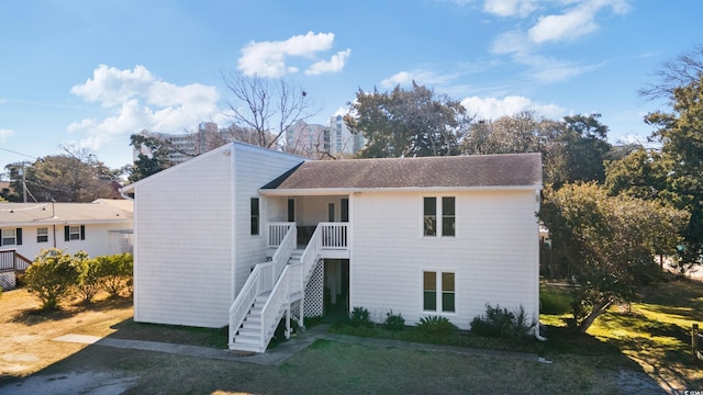 view of front of home with stairway, a front lawn, roof with shingles, and covered porch