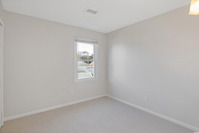 spare room featuring light colored carpet and baseboards