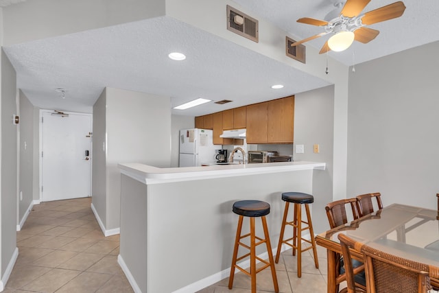 5806 N Ocean Blvd Unit 203, North Myrtle Beach, SC 29582 - kitchen featuring freestanding refrigerator, under cabinet range hood, light tile patterned flooring, a peninsula, and a textured ceiling