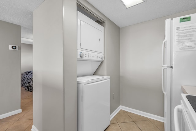 5806 N Ocean Blvd Unit 203, North Myrtle Beach, SC 29582 - washroom featuring stacked washer / drying machine, light tile patterned floors, a textured ceiling, and baseboards