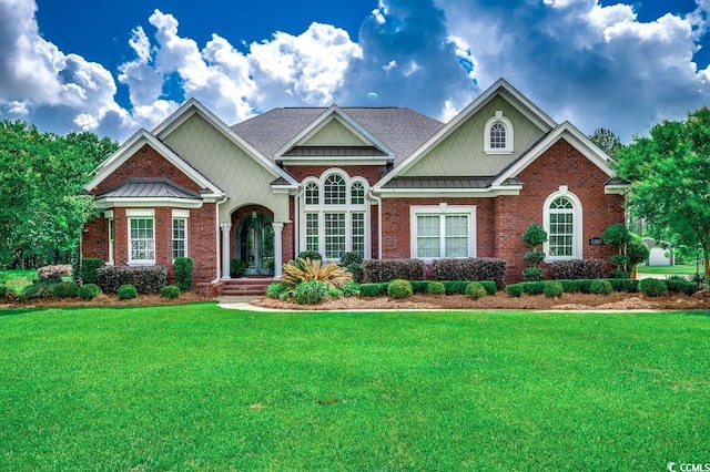 craftsman-style home with a front yard, brick siding, a standing seam roof, and metal roof