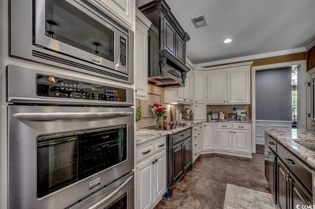 kitchen with stainless steel appliances, ornamental molding, tasteful backsplash, light stone counters, and dark stone finish flooring