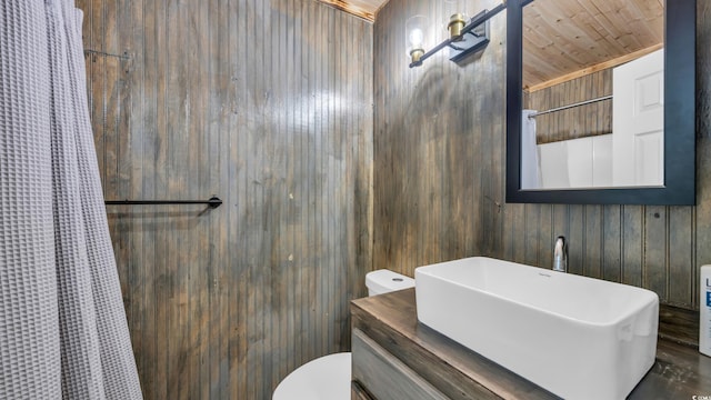 full bathroom featuring wooden walls, toilet, a shower with curtain, and vanity