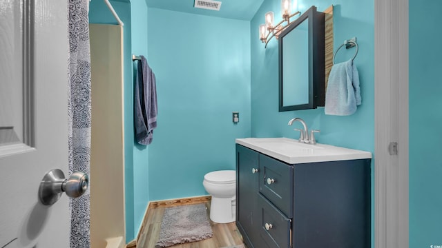 bathroom with wood finished floors, vanity, toilet, curtained shower, and baseboards