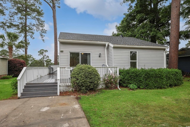 view of front facade with a deck, a front lawn, and a shingled roof