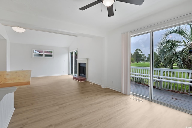 unfurnished living room with wood finished floors, ceiling fan, plenty of natural light, and lofted ceiling