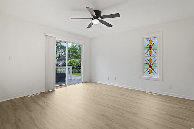 spare room featuring light wood finished floors, a ceiling fan, and baseboards