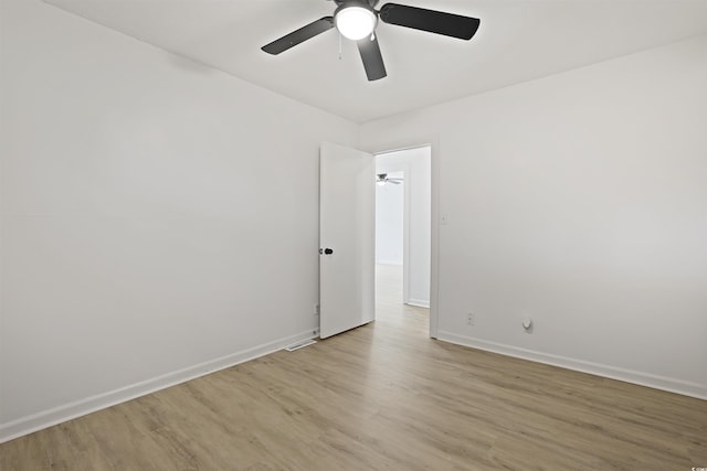 spare room featuring light wood finished floors, ceiling fan, and baseboards
