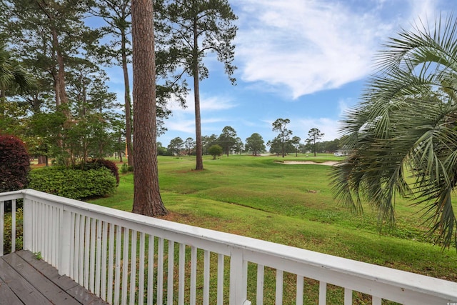deck with view of golf course and a yard