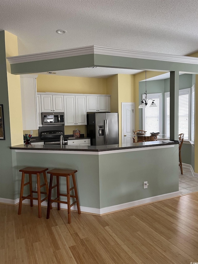 3012 Winding River Rd, North Myrtle Beach, SC 29582 - kitchen featuring stainless steel appliances, dark countertops, light wood-style flooring, a textured ceiling, and white cabinets