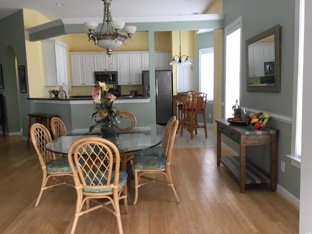 3012 Winding River Rd, North Myrtle Beach, SC 29582 - dining area featuring a chandelier, healthy amount of natural light, arched walkways, and light wood-style flooring
