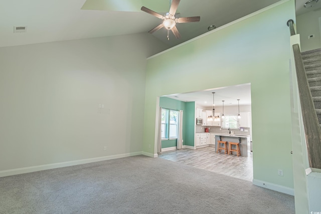 395 Dunbarton Ln, Conway, SC 29526 - unfurnished living room featuring light carpet, a ceiling fan, baseboards, high vaulted ceiling, and a chandelier
