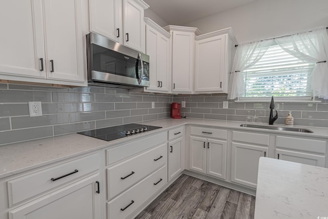 395 Dunbarton Ln, Conway, SC 29526 - kitchen with stainless steel microwave, black electric stovetop, a sink, white cabinetry, and decorative backsplash