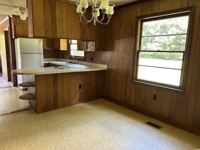 kitchen with freestanding refrigerator, wooden walls, light countertops, and healthy amount of natural light