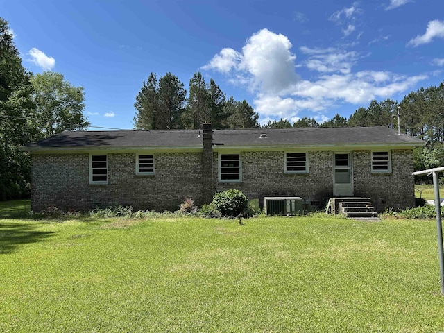 back of house featuring brick siding, cooling unit, and a lawn