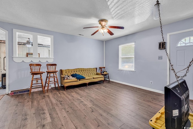 sitting room with a ceiling fan, wood-type flooring, a textured ceiling, and baseboards