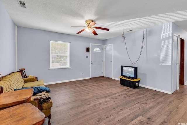 living room featuring ceiling fan, a textured ceiling, wood finished floors, and baseboards
