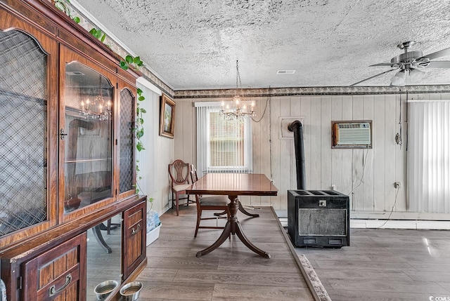 dining space with an AC wall unit, a chandelier, wood finished floors, a textured ceiling, and ceiling fan