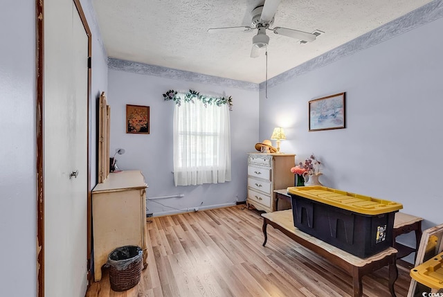 bedroom with a textured ceiling, light wood finished floors, baseboards, and a ceiling fan