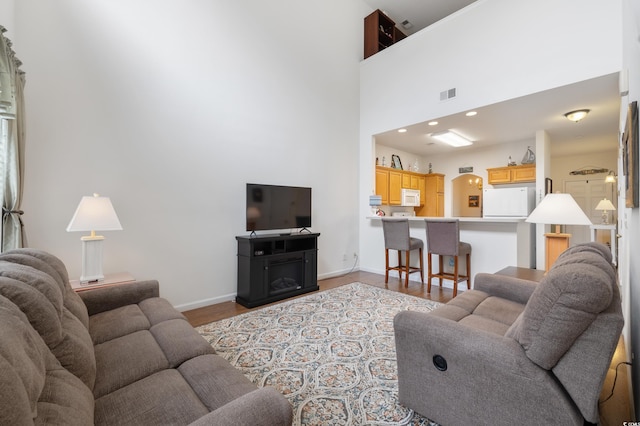 living room with baseboards, wood finished floors, and a high ceiling
