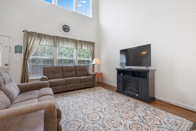 living room featuring a high ceiling, plenty of natural light, baseboards, and wood finished floors