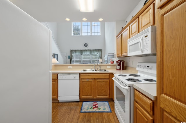 kitchen featuring white appliances, a sink, light countertops, wood finished floors, and recessed lighting