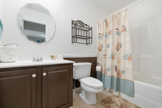 full bath with a wainscoted wall, toilet, tile patterned flooring, vanity, and shower / tub combo with curtain