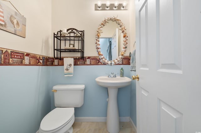 bathroom with toilet, a sink, and baseboards