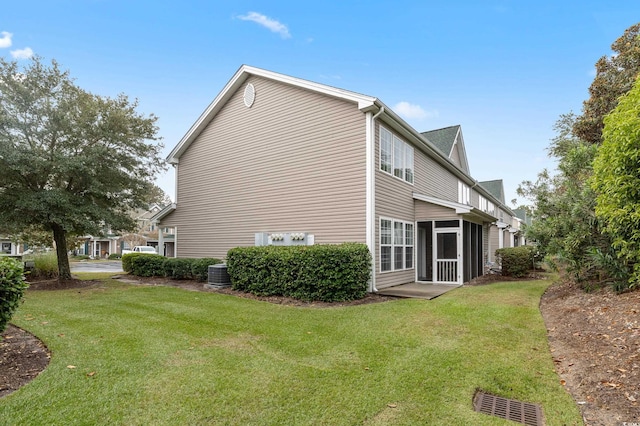 view of side of property featuring a lawn, a sunroom, and central air condition unit