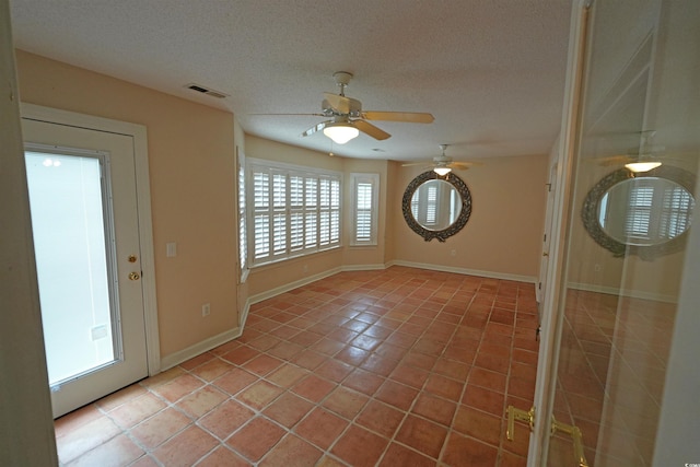 entrance foyer with light tile patterned flooring, a textured ceiling, ceiling fan, and baseboards