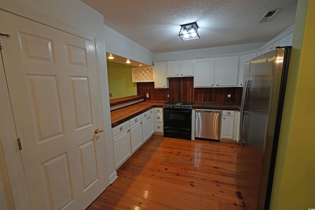 kitchen with appliances with stainless steel finishes, white cabinets, a textured ceiling, and light wood-type flooring