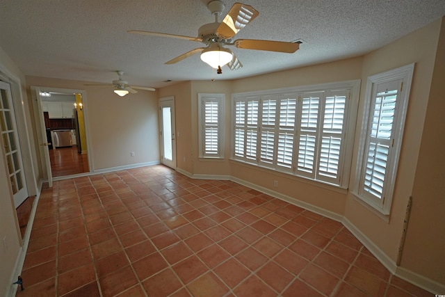 unfurnished room with tile patterned flooring, a textured ceiling, baseboards, and ceiling fan