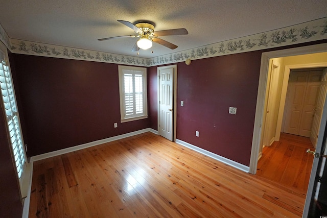 spare room featuring light wood-style flooring, a ceiling fan, baseboards, and a textured ceiling