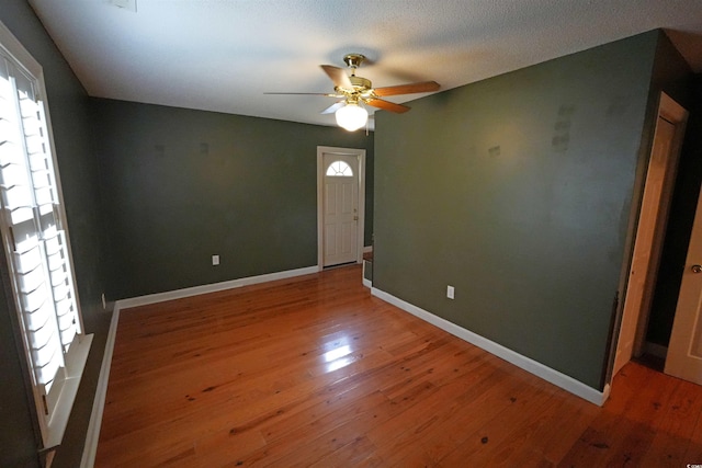spare room with ceiling fan, hardwood / wood-style floors, and baseboards